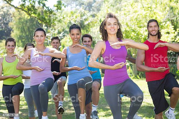 Fitness group doing tai chi in park on a sunny day